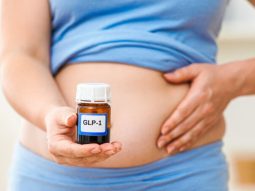 GLP-1 vial held by overweight person on stomach, weight loss, healthcare concept, medical treatment, diabetes management, metabolic health research, pharmaceutical marketing, clinical study imagery default rsz adobestock 1811758881