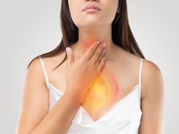 A woman suffering from acid reflux or Heartburn on gray Backgrou reflusso gastroesofageo cause e rimedi