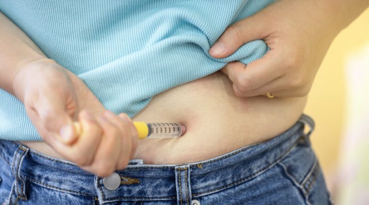 A woman injecting herself with obesity medication rsz adobestock 894317698