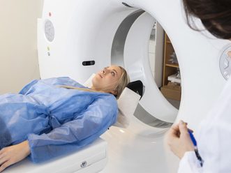 Patient Lying On MRI Machine While Doctor Operating It tecnico sanitario di radiologia medica